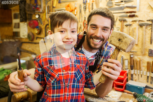 Image of boy with dad holding chisel and hammer at workshop