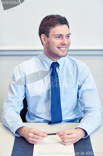 Image of smiling businessman sitting in office