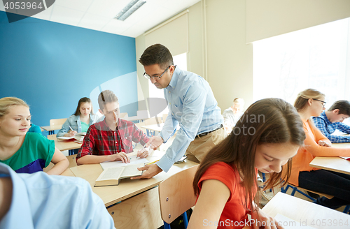 Image of teacher helping students with task at school