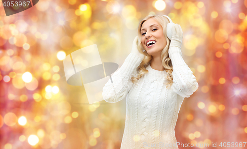 Image of smiling young woman in winter earmuffs and sweater