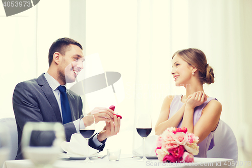 Image of man proposing to his girlfriend at restaurant