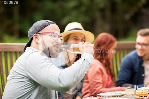 Image of man drinking beer with friends at summer party