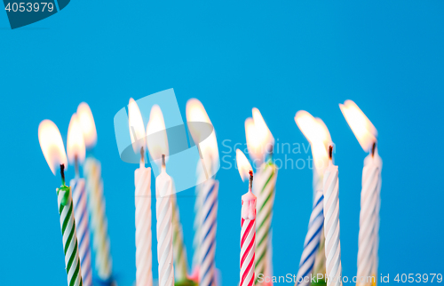 Image of birthday candles burning over blue background