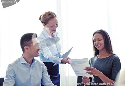 Image of smiling business people with papers in office