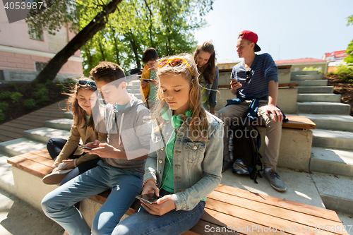 Image of group of teenage friends with smartphones outdoors