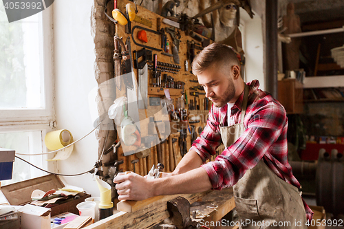 Image of carpenter working with plane and wood at workshop