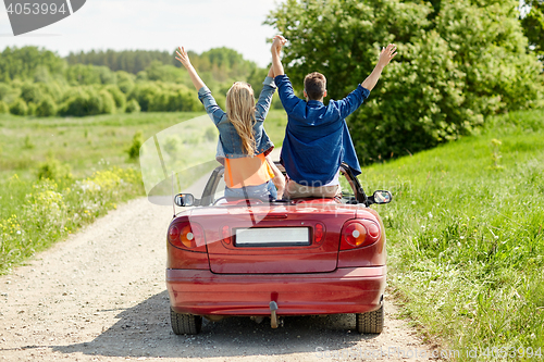 Image of happy friends driving in cabriolet car at country