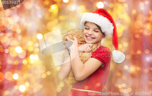 Image of smiling girl in santa helper hat with teddy bear