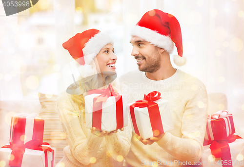 Image of happy couple at home exchanging christmas gifts