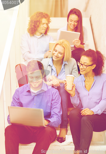 Image of team with laptop and tablet pc on staircase