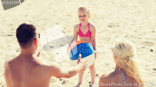 Image of happy family playing with inflatable ball on beach