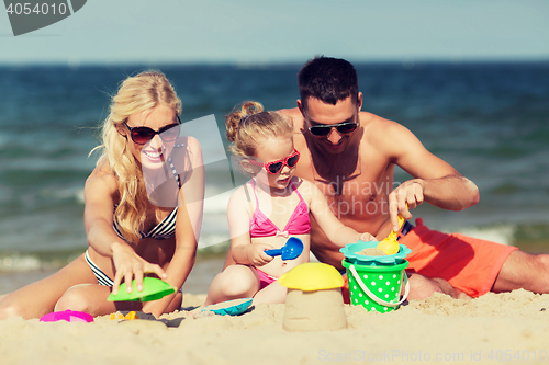 Image of happy family playing with sand toys on beach