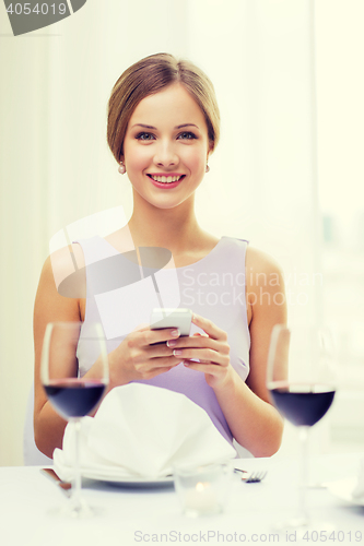 Image of smiling woman with smartphone at resturant