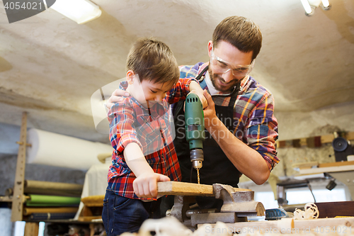 Image of father and son with drill working at workshop