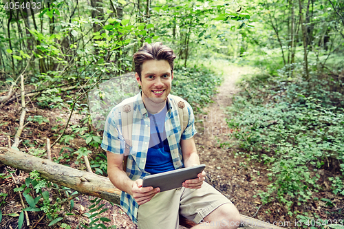 Image of happy man with backpack and tablet pc in woods