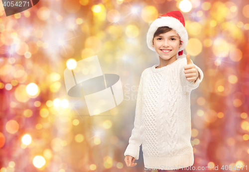 Image of smiling happy boy in santa hat showing thumbs up