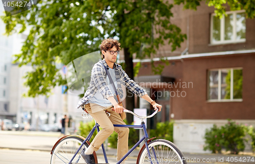 Image of young hipster man with bag riding fixed gear bike