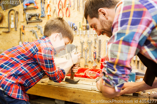 Image of father and son with hammer working at workshop