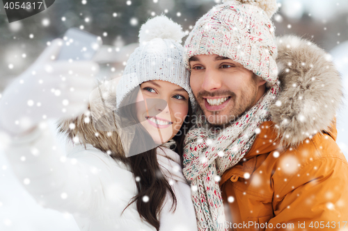 Image of happy couple taking selfie by smartphone in winter