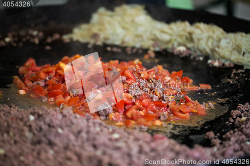 Image of vegetables frying on big wok pan at street market