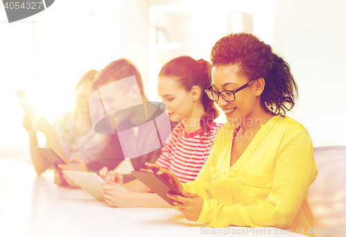 Image of smiling students looking at tablet pc at school