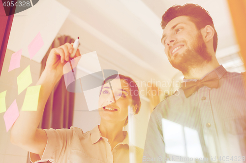 Image of happy creative team writing on blank office glass