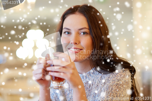 Image of smiling young woman drinking tea at cafe