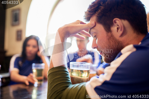 Image of soccer fans watching football match at bar or pub
