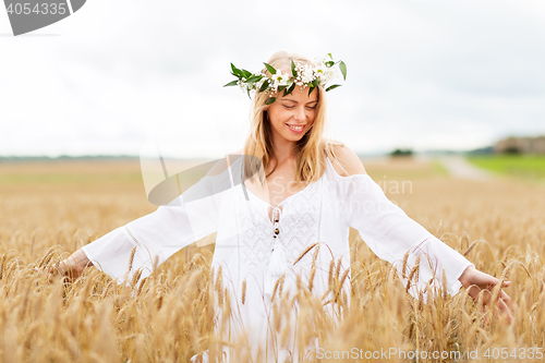 Image of happy young woman in flower wreath on cereal field