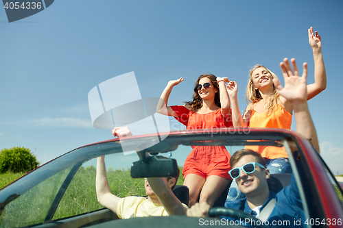 Image of happy friends driving in cabriolet car