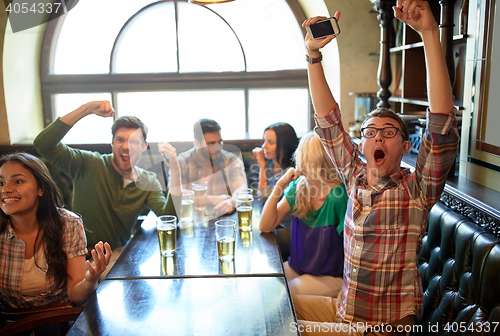 Image of friends with beer watching football at bar or pub