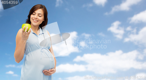 Image of happy pregnant woman looking at green apple