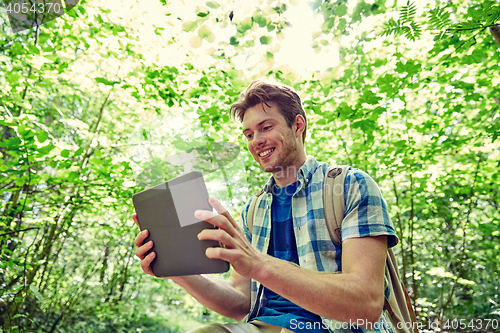 Image of happy man with backpack and tablet pc in woods