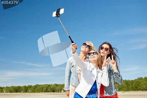 Image of group of smiling women taking selfie on beach