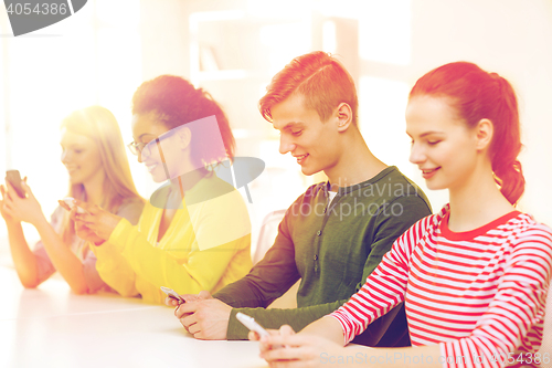 Image of four smiling students with smartphones at school