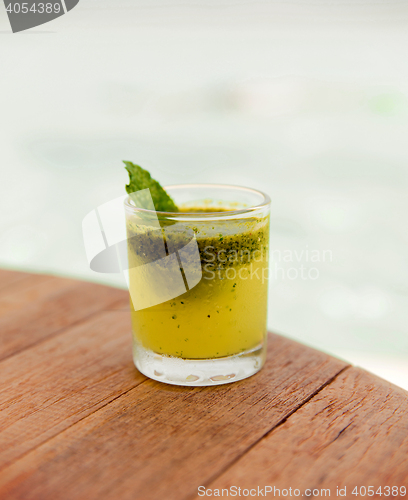 Image of glass of fresh juice or cocktail on table at beach