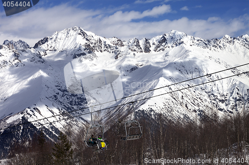 Image of Skiers on ski-lift at winter sun day