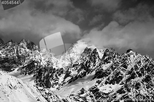 Image of Black and white snowy rocks in clouds at sun winter day