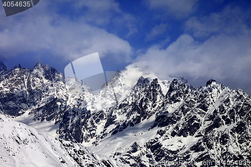 Image of Snowy rocks in clouds at sun winter day