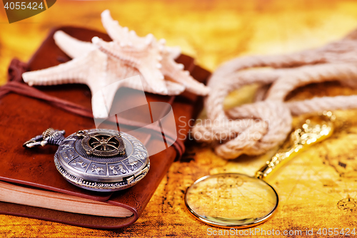 Image of old notebook, loupe and compass on the map