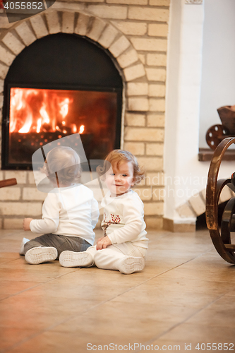 Image of The two little girls sitting at home against fireplace