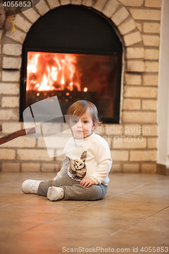 Image of Happy child little girl sitting at home against fireplace