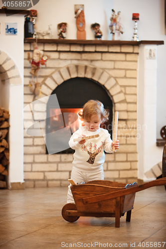 Image of The little girl standing at home against fireplace