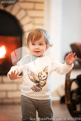 Image of Happy child little girl standing at home against fireplace