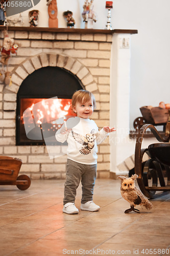 Image of Happy child little girl standing at home against fireplace