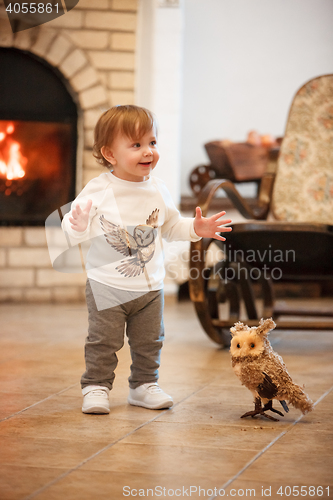 Image of Happy child little girl standing at home against fireplace