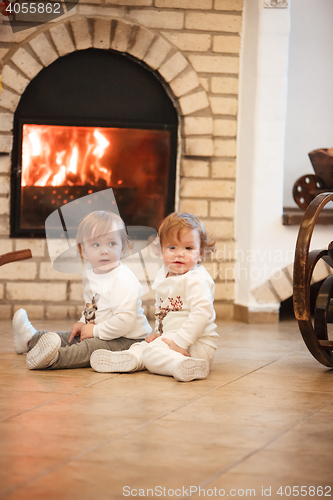 Image of The two little girls sitting at home against fireplace