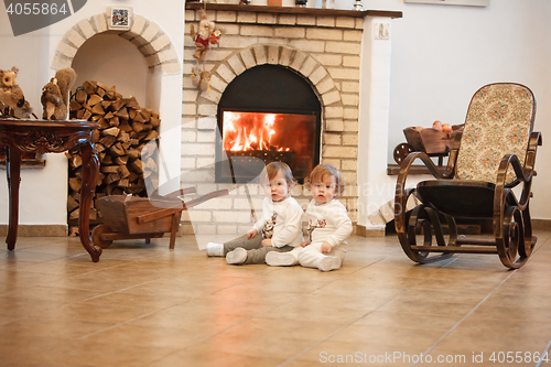 Image of The two little girls sitting at home against fireplace