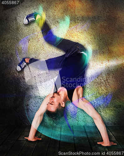 Image of Break dancer doing handstand against colorful wall background