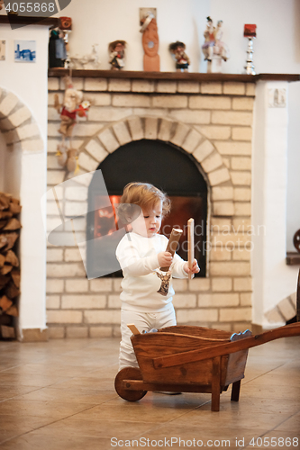 Image of The little girl standing at home against fireplace